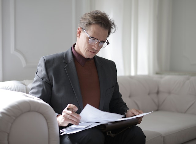 person-sitting-on-couch-reading-over-lease-agreement