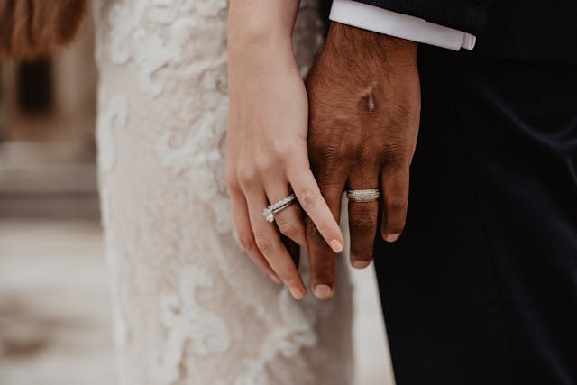 two-people-wearing-silver-weddig-bands-with-some-fingers-intertwined