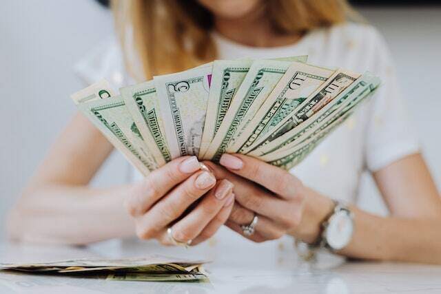 person holding rent dollar bills splayed out in their hands